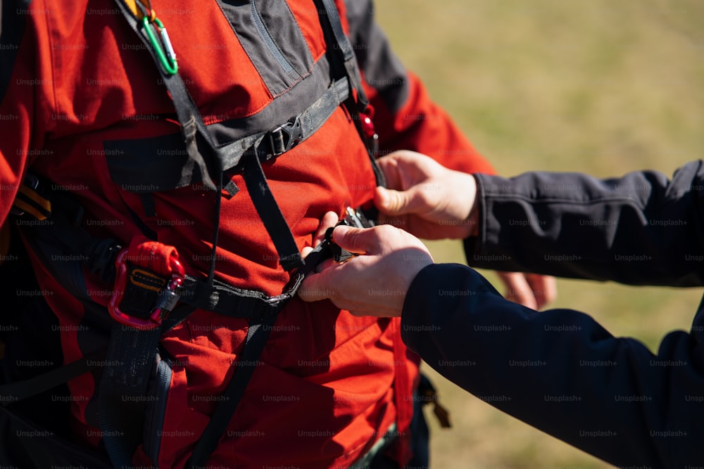Um close-up de um homem ajudando o piloto de parapente a se preparar para o voo.