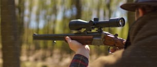 Un cazador apuntando con una pistola de rifle a una presa en el bosque.