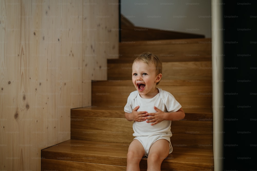 A cute little girl sitting on stairs at home.