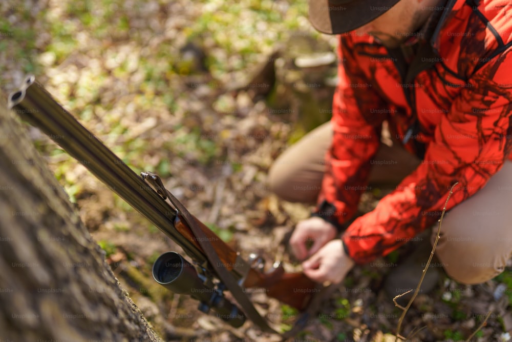 Un cazador con una pistola de rifle esperando a una presa en el bosque.
