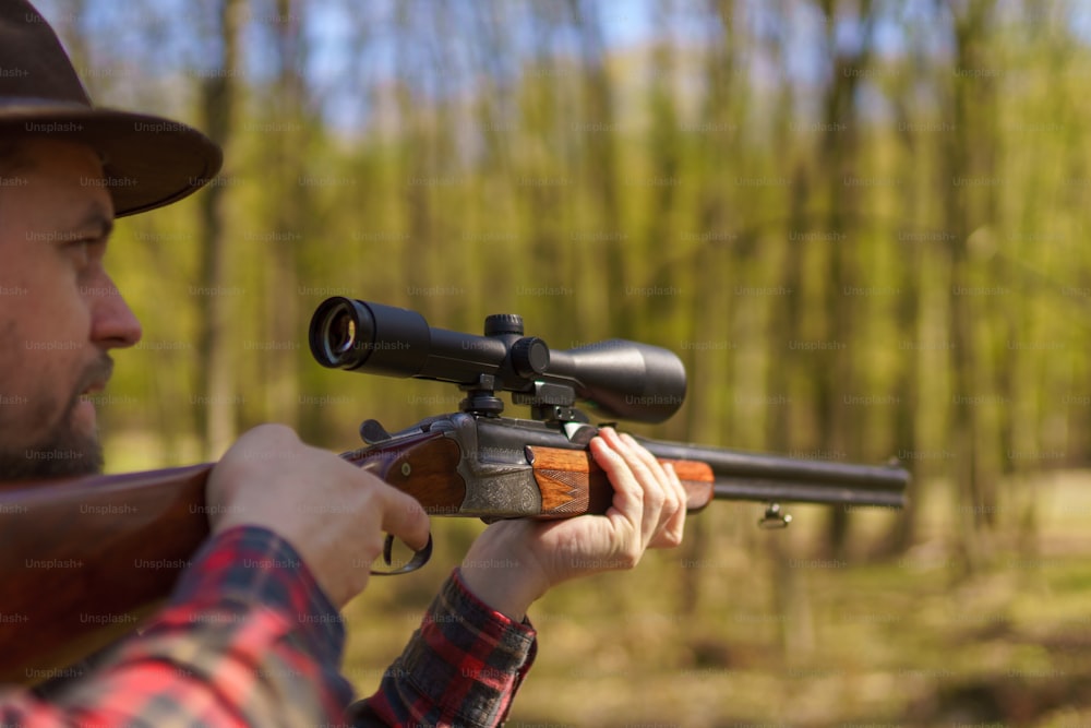 Um caçador mirando com arma de fuzil em presas na floresta.
