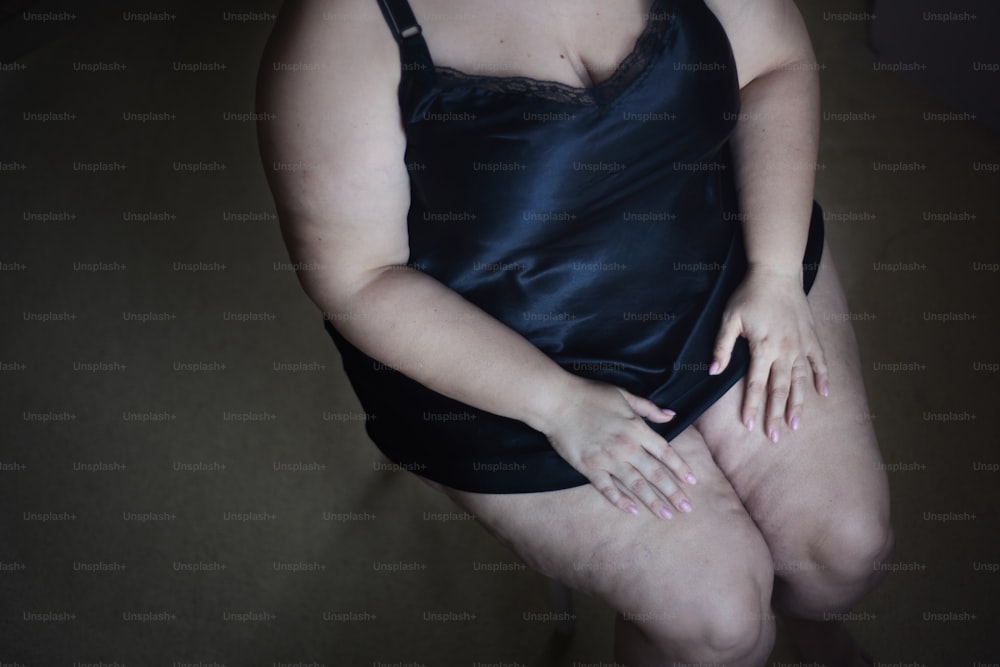 A midsection of lonely fat woman in underwear sitting on chair at home.