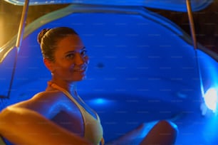 A beautiful woman floating in tank filled with dense salt water used in medical therapy, looking at camera.
