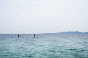 Men spending leisure time while enjoying paddling on a SUP in sea during summer. Summer vacation concept.