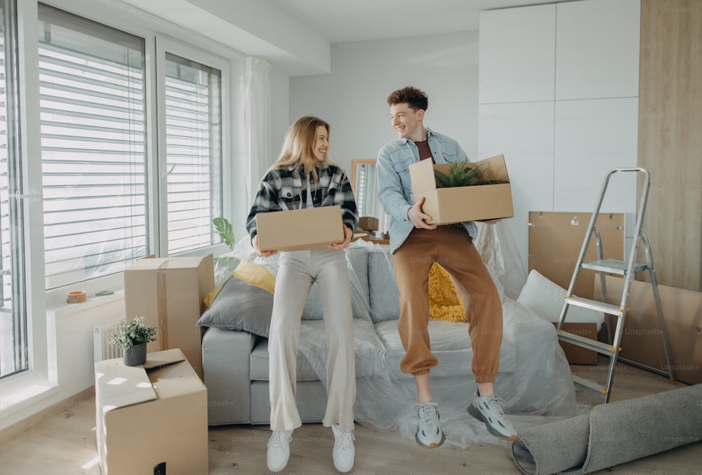 Un jeune couple joyeux dans leur nouvel appartement, portant des cartons. Conception de déménagement.