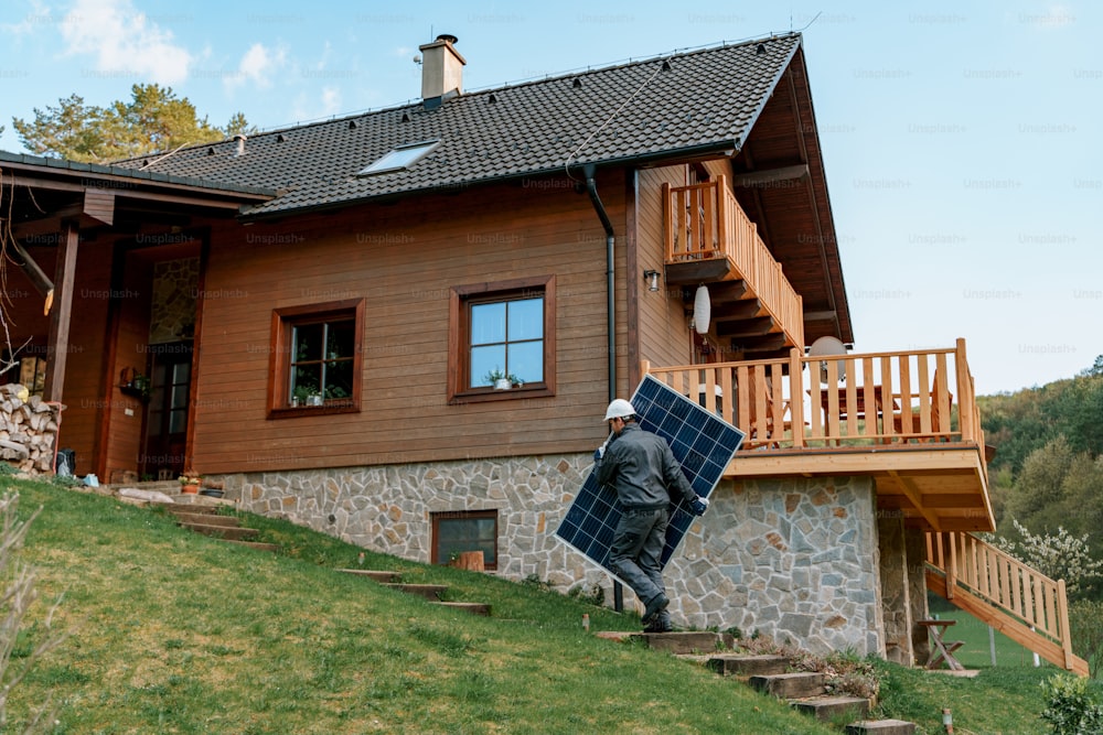 Un ouvrier portant un panneau solaire pour l’installation d’un système de module solaire sur la maison.