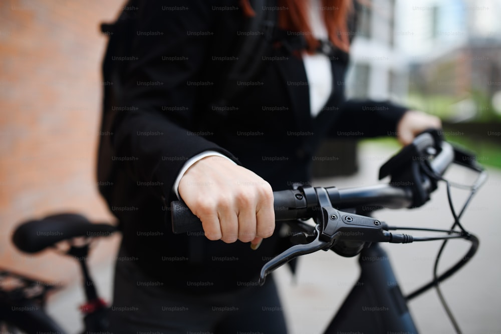 自転車、ホールディンハンドル、持続可能なライフスタイルのコンセプトで通勤途中のビジネスウーマン通勤者のクローズアップ。