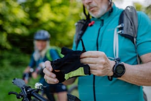 Close-up of a senior man biker putting on bicycle gloves.