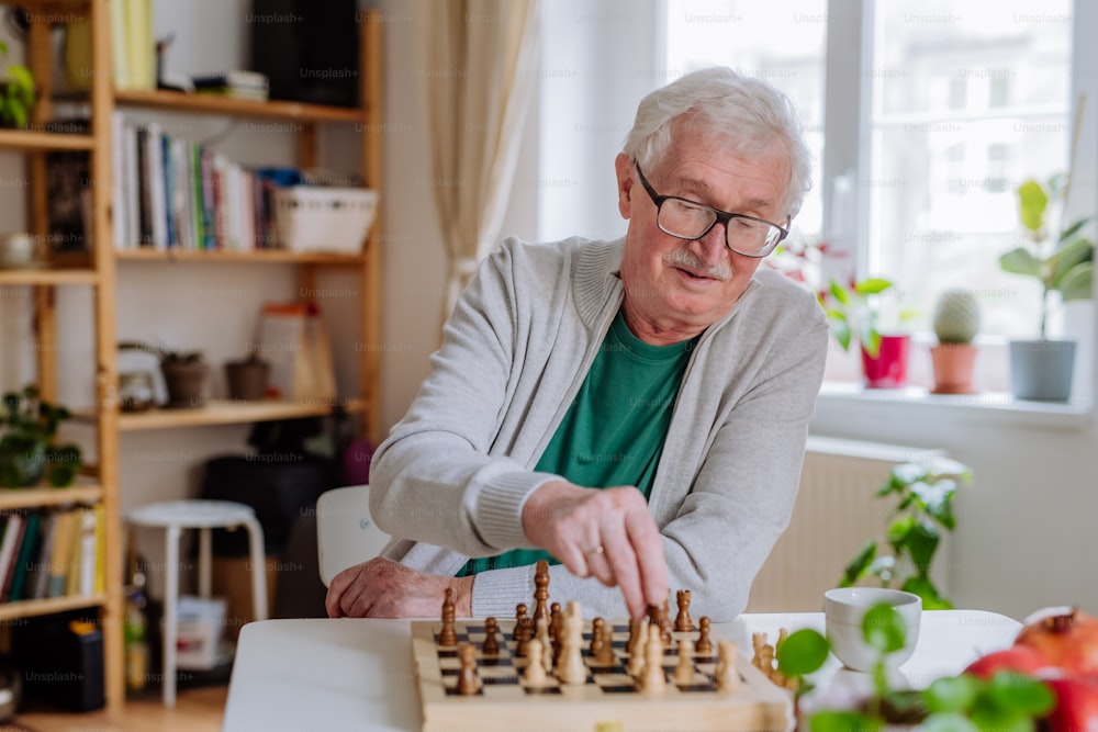A senior man playing a chess at home.