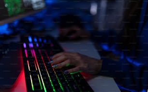 Close-up of a woman hacker hands at keyboard computer in the dark room at night, cyberwar concept. Side view.
