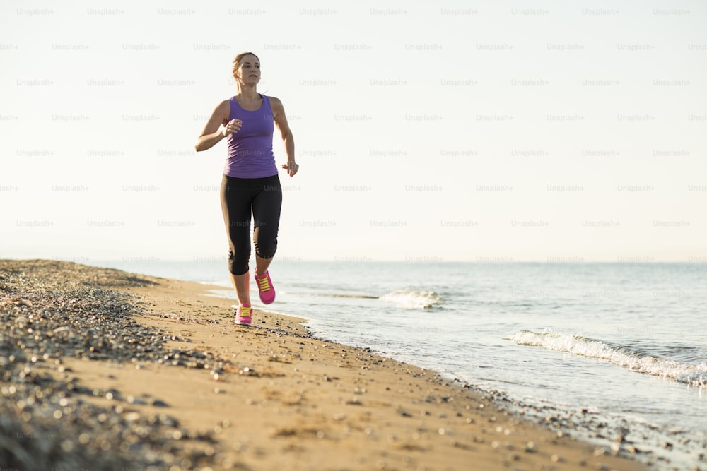 Young woman is running in sunny nature along the beach