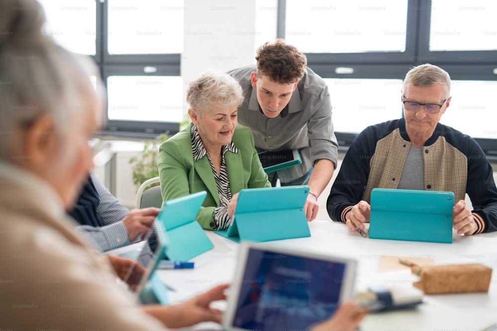 Un grupo de personas mayores que asisten a una clase de informática en un centro comunitario con un profesor