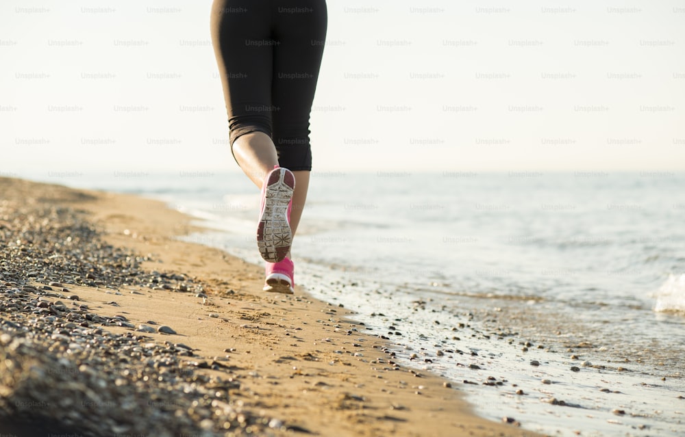 Young woman is running in sunny nature along the beach