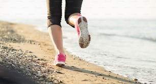 Young woman is running in sunny nature along the beach