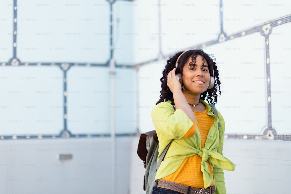 A young biracial woman wearing headphones and enjoying listening to music outdoors in street.