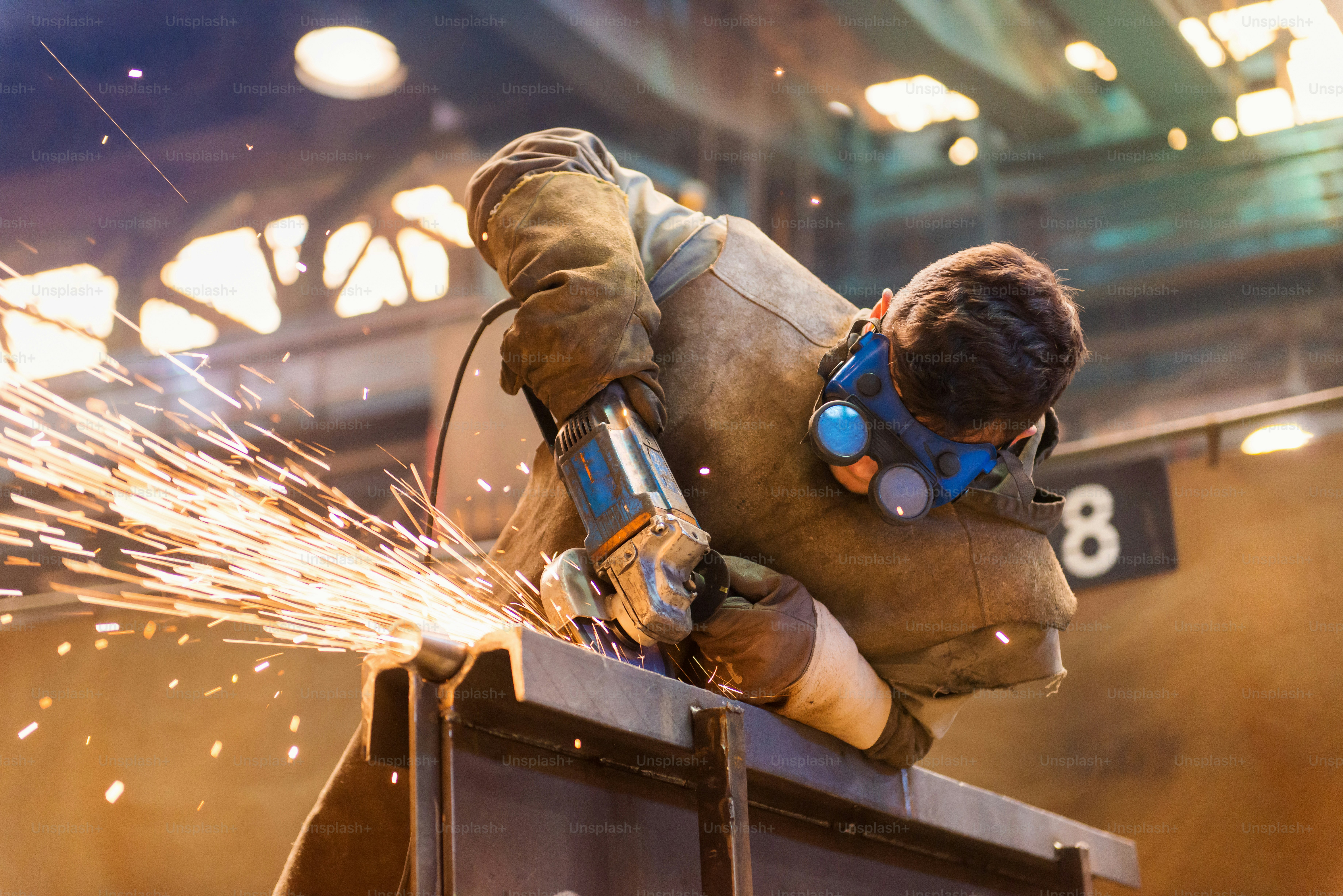 Young man with protective goggles welding in a factory