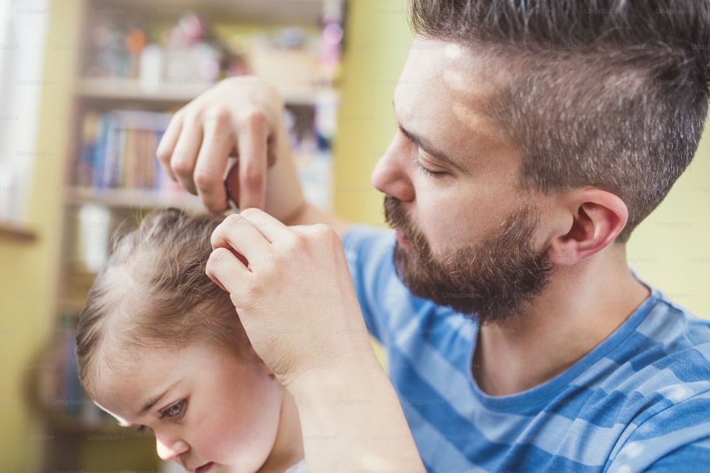 Young father styling hair of his daughter