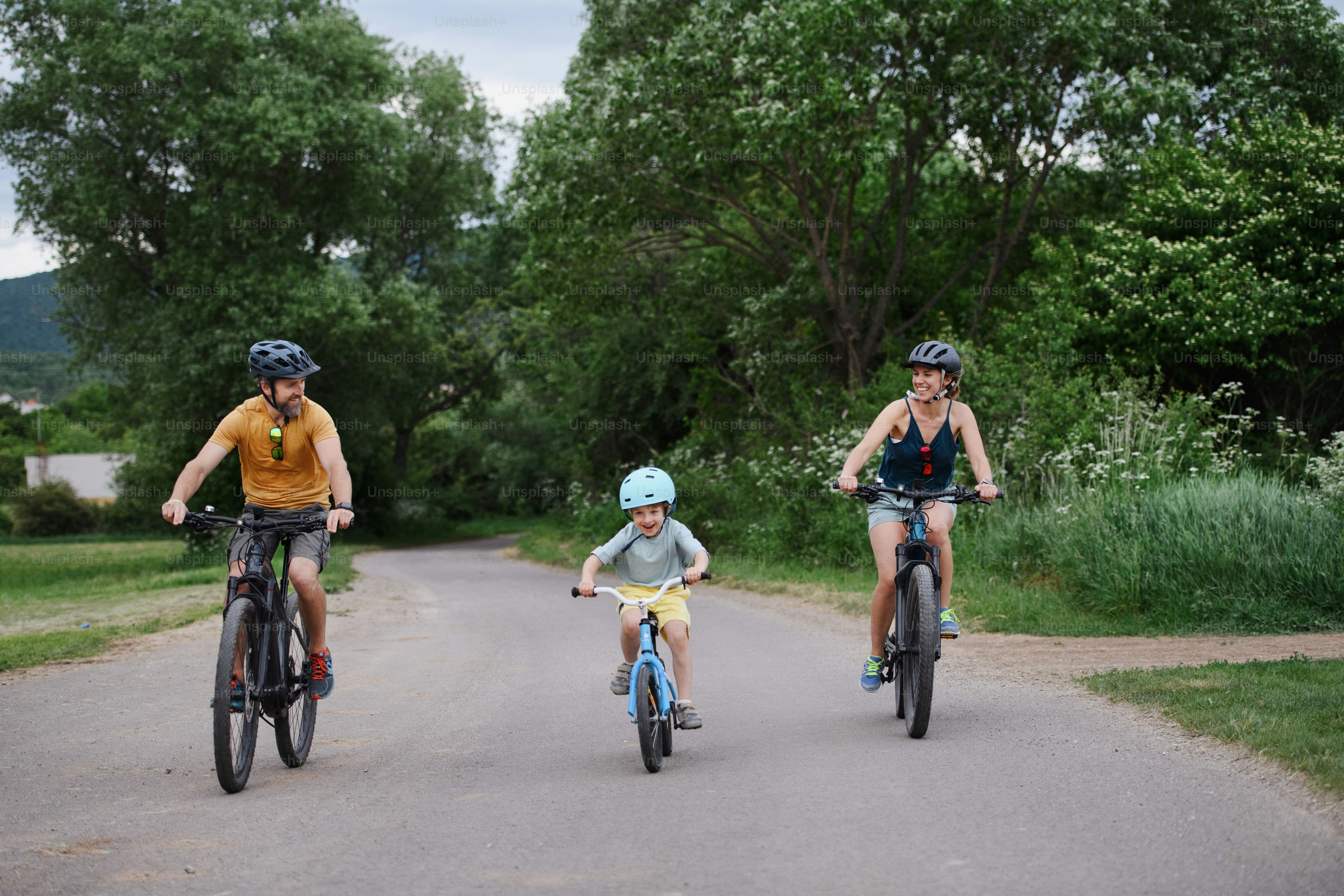 Una familia joven con un niño pequeño montando bicicletas en la carretera en el pueblo en verano