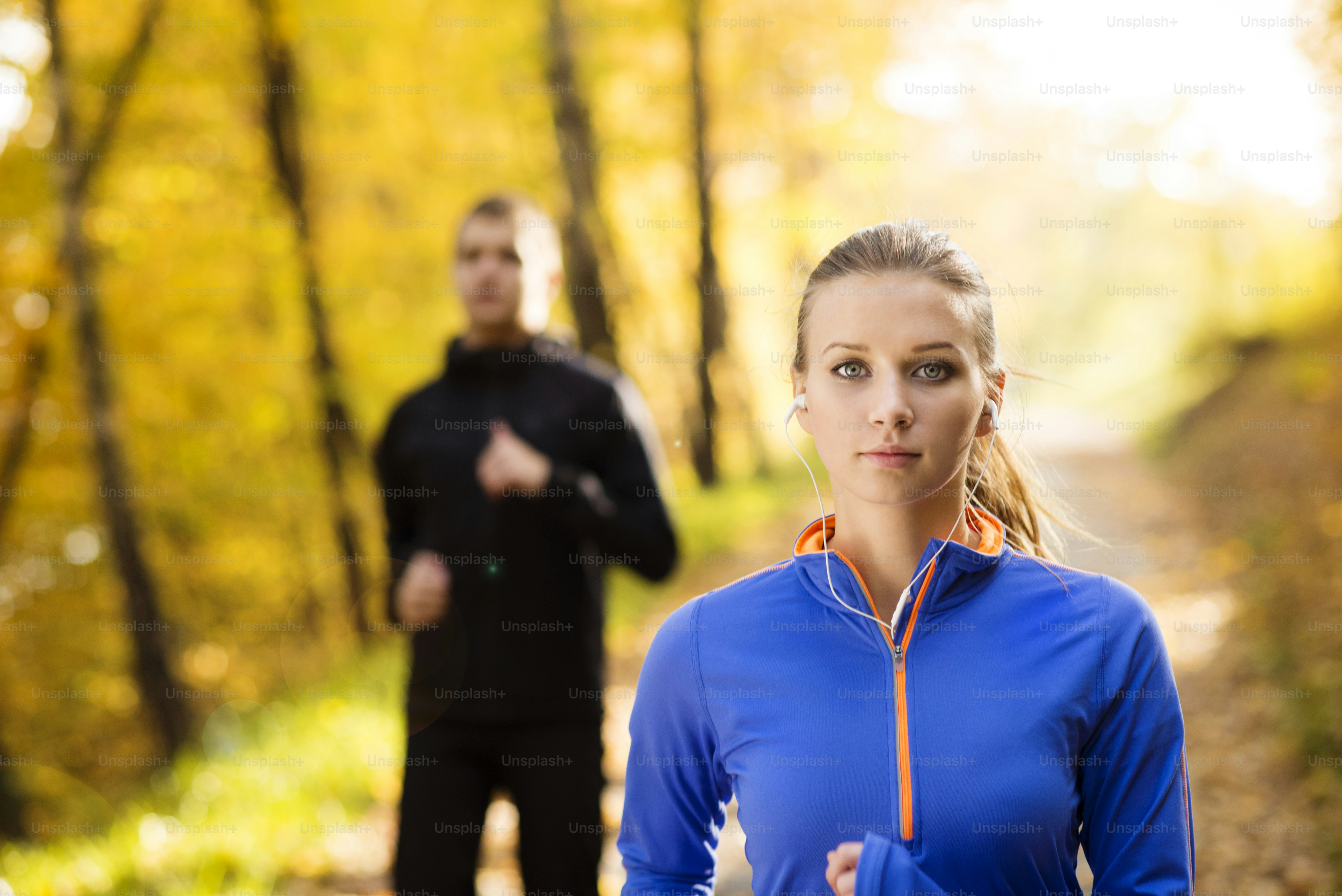 Young running couple jogging in autumn nature