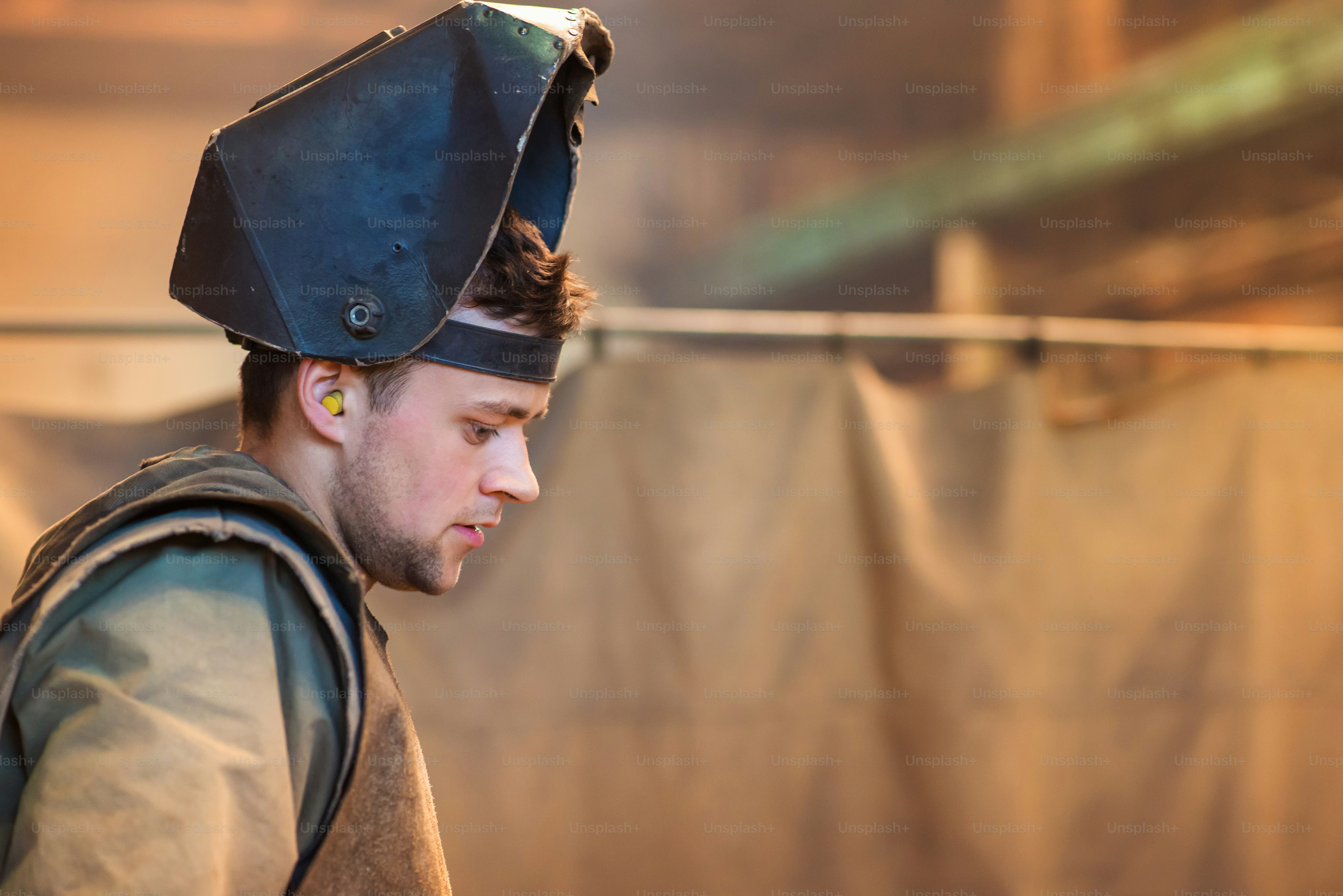Young man with protective mask welding in a factory