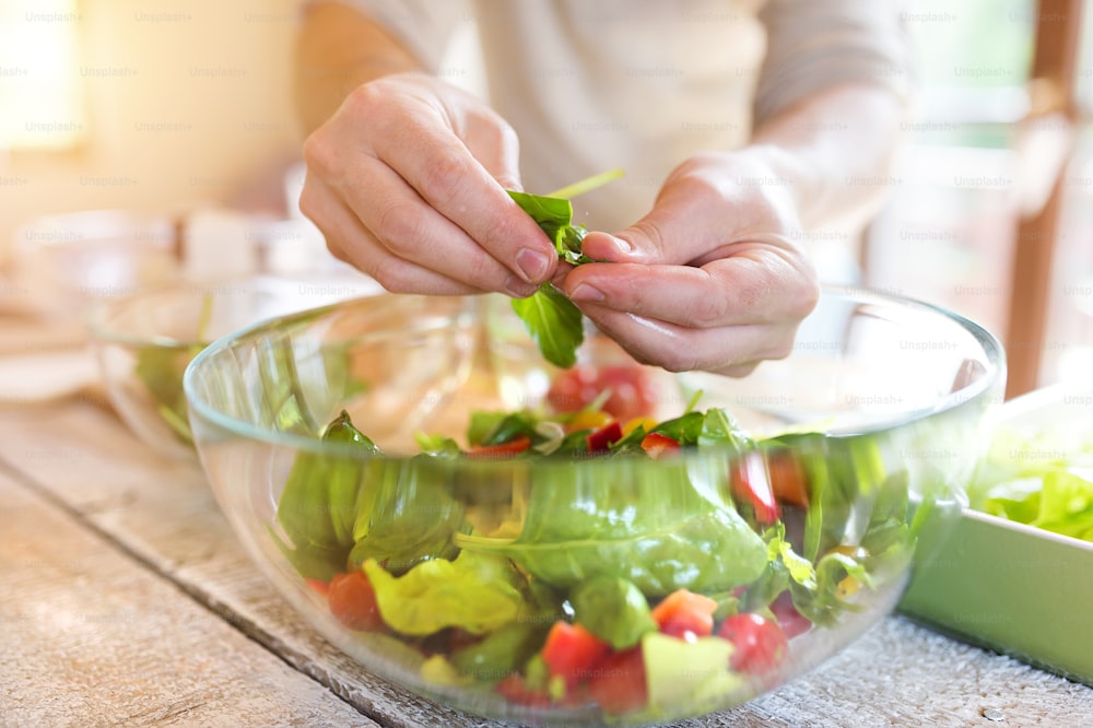 Homem irreconhecível preparando ingredientes para salada de vegetais