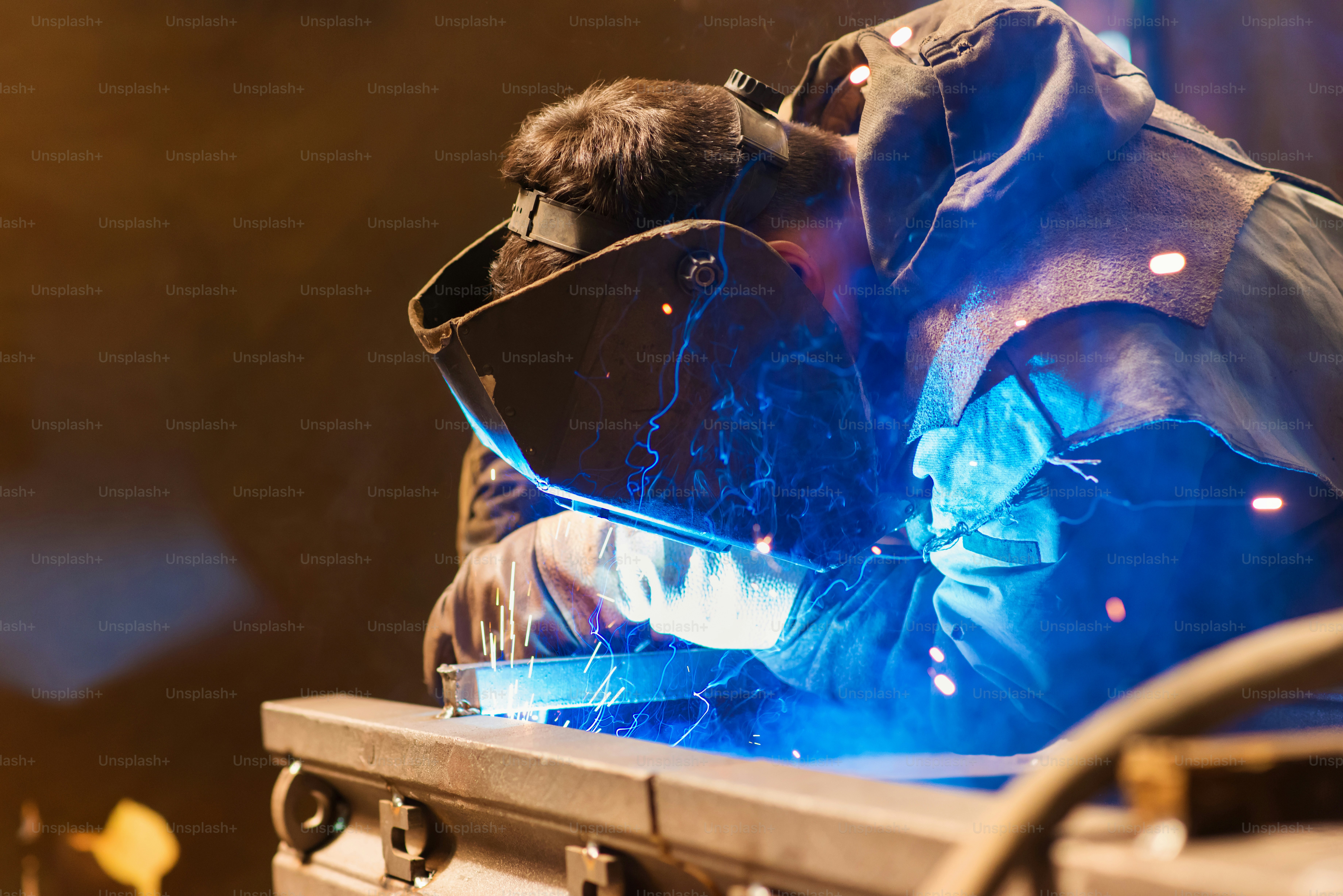 Young man with protective mask welding in a factory