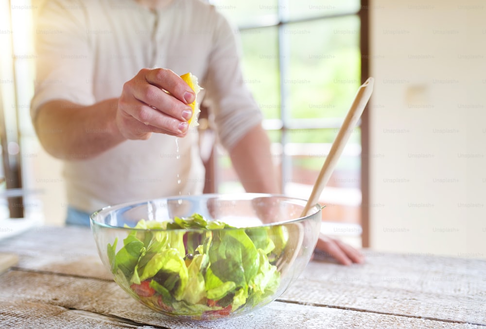 Homem irreconhecível preparando ingredientes para salada de vegetais