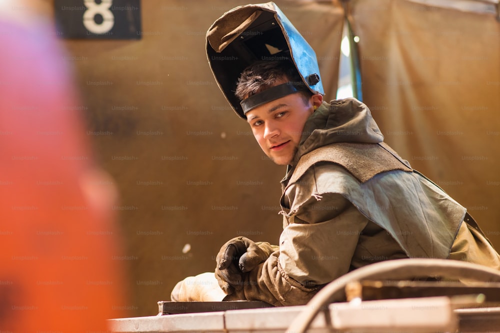 Young man with protective mask welding in a factory