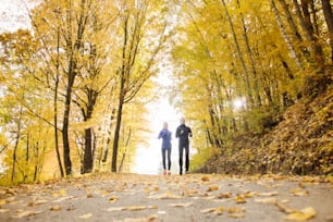 Jeune couple de coureurs faisant du jogging dans la nature d’automne