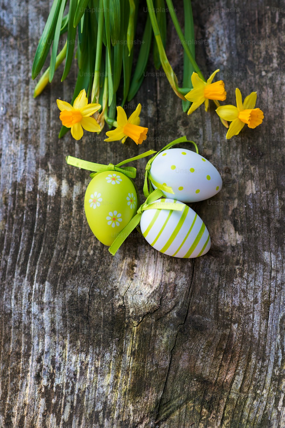 Colorful easter eggs and beautiful spring flowers laid on a wooden floor background.