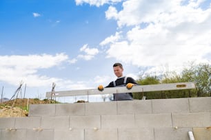 Bricklayer with a level checking another row of bricks