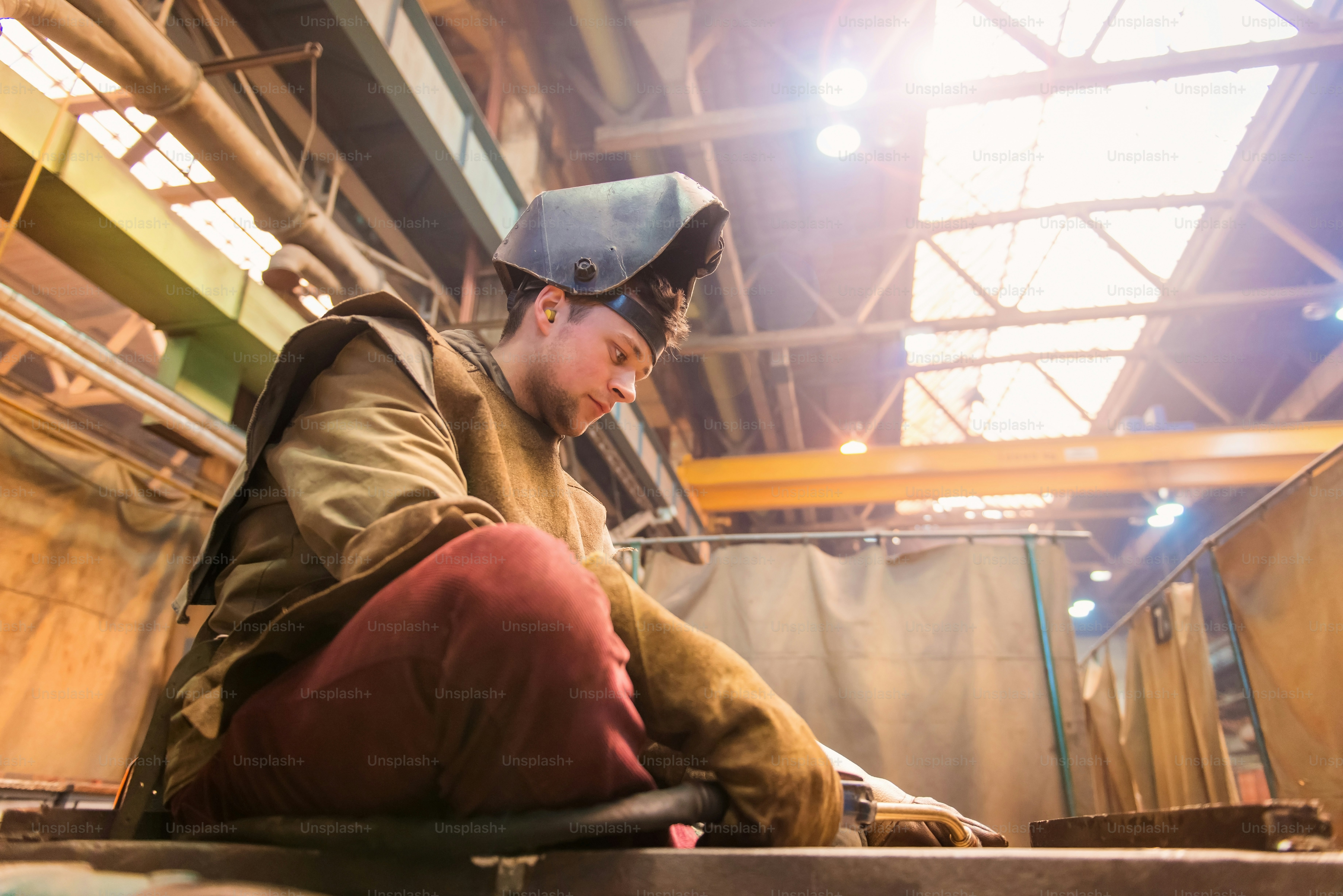 Young man with protective mask welding in a factory