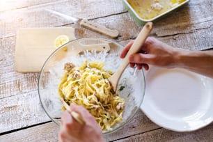 Man serving salmon tagliatelle on a plate.