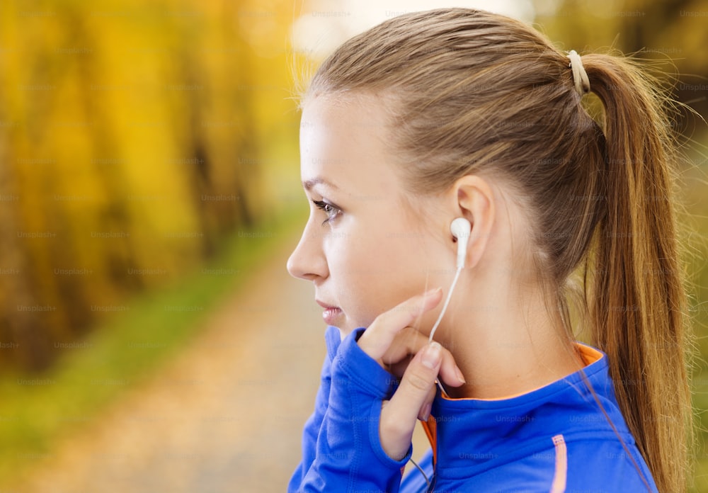 Sportliche und aktive Läuferin hört Musik vor dem Training im Freien