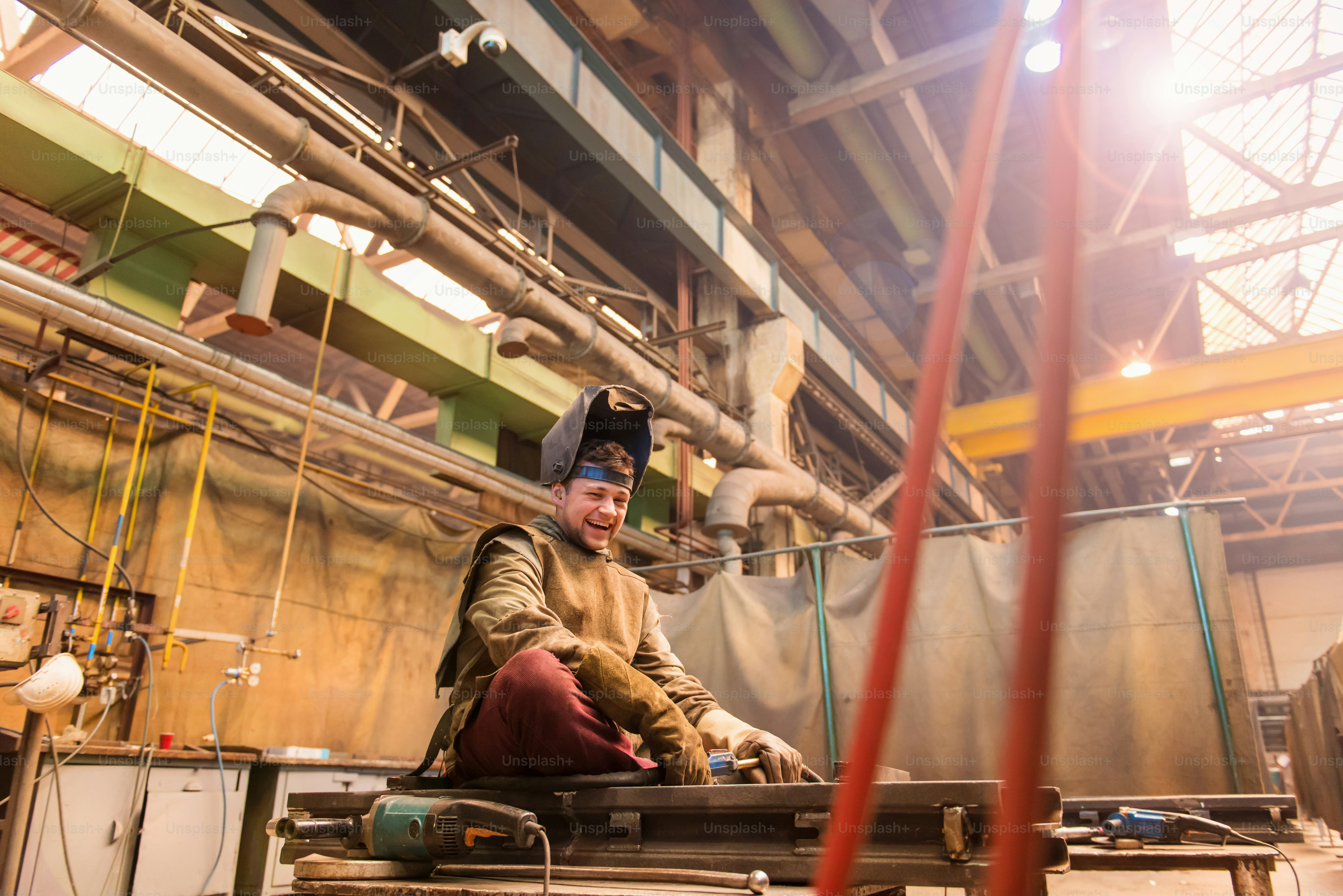 Young man with protective mask welding in a factory