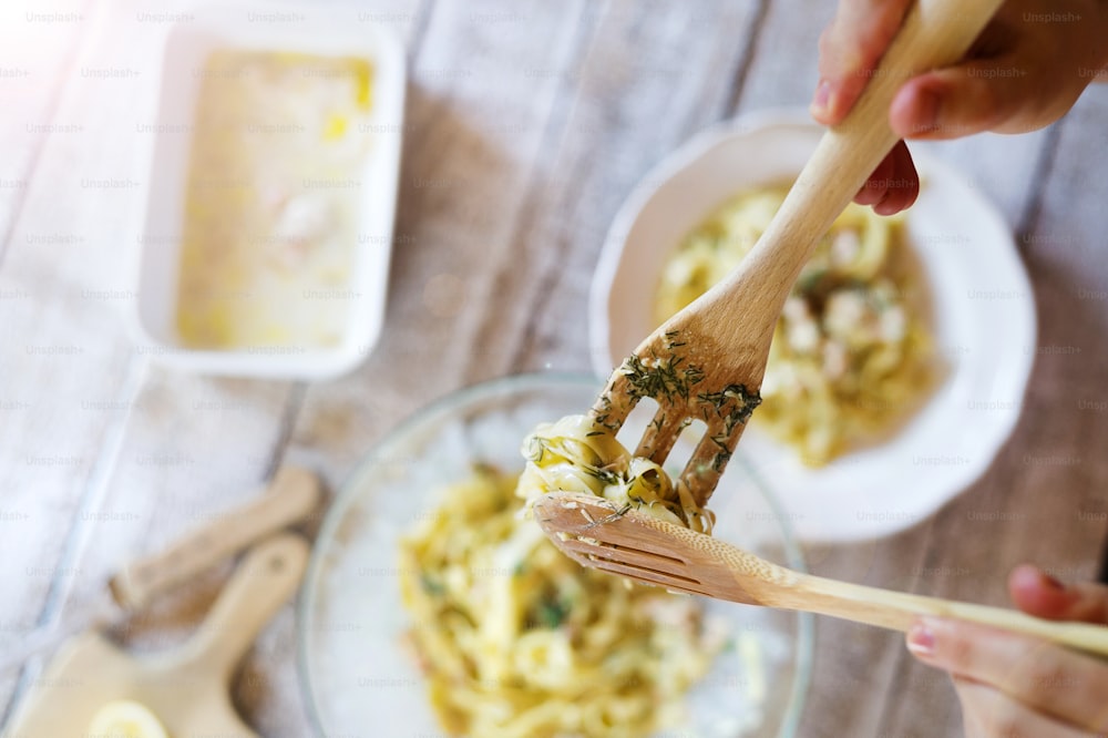 Man serving salmon tagliatelle on a plate.