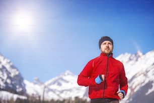 Young sportsman jogging outside in sunny winter park