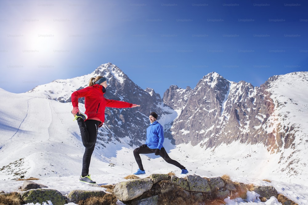 Junges Paar joggt draußen in sonnigen Winterbergen