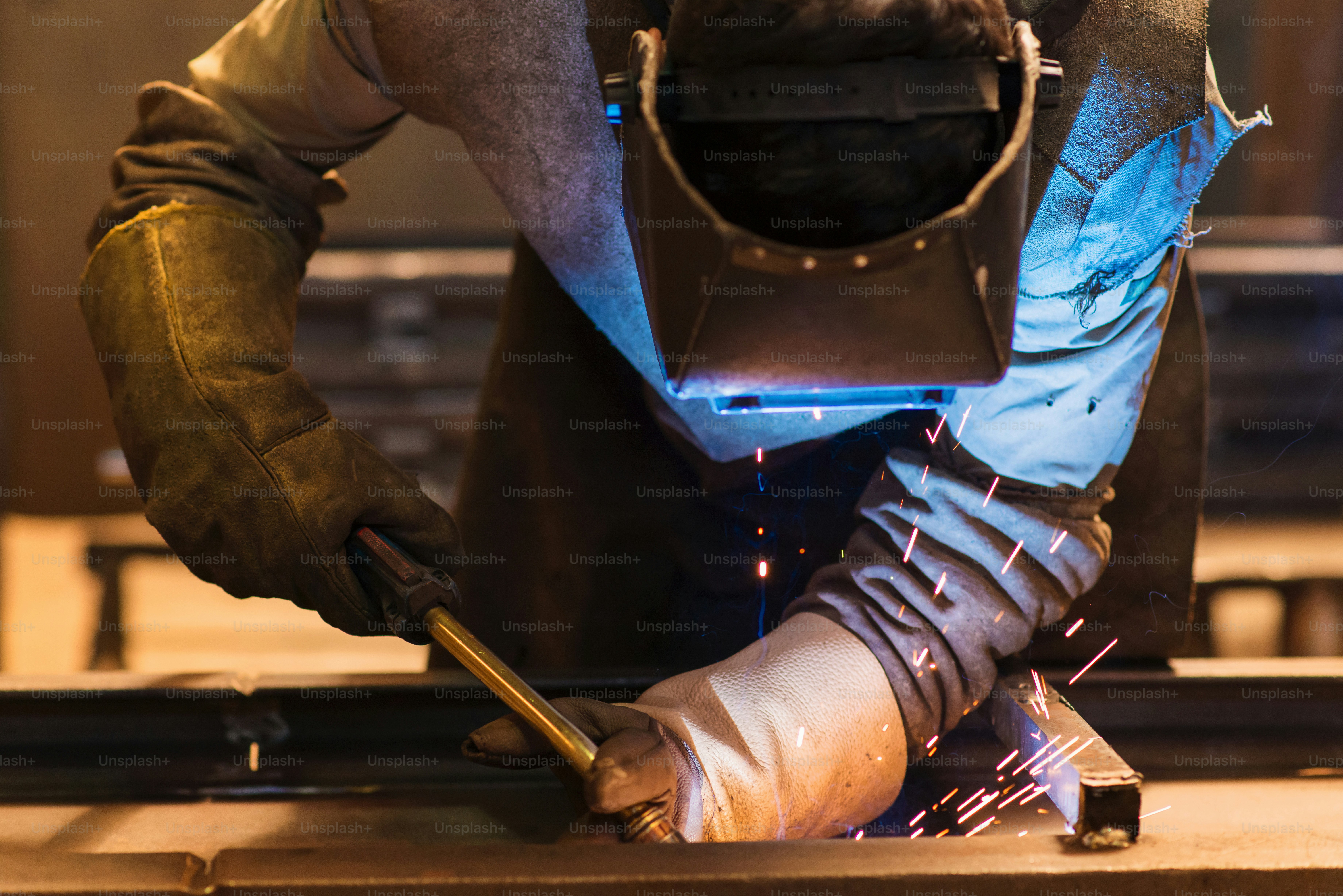 Young man with protective mask welding in a factory