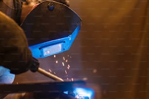 Young man with protective mask welding in a factory