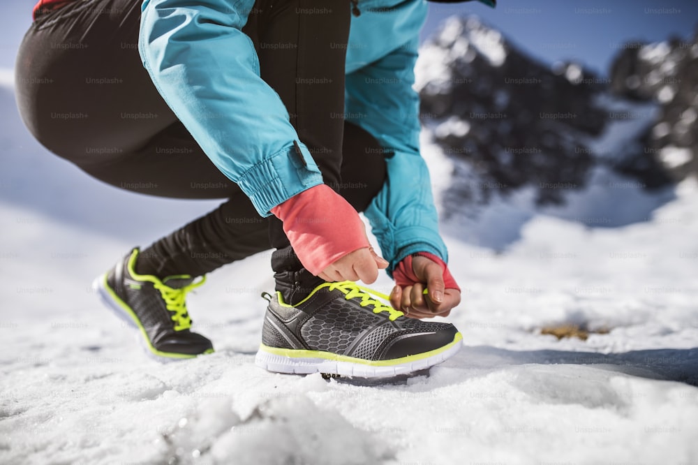 日当たりの良い冬の山々で外をジョギングする見分けのつかない女性