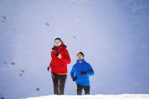 Young couple jogging outside in sunny winter mountains