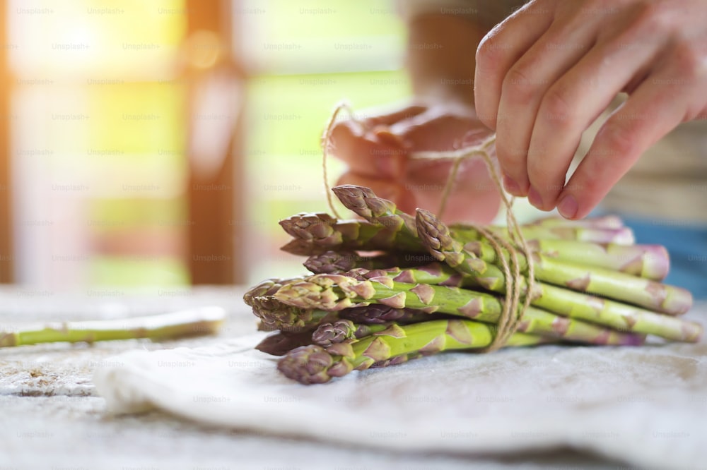 Bunch of fresh green asparagus spears tied with twine on a rustic wooden table