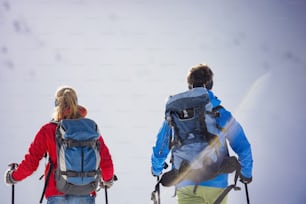 햇볕이 잘 드는 겨울 산에서 야외 하이킹을 하는 젊은 부부
