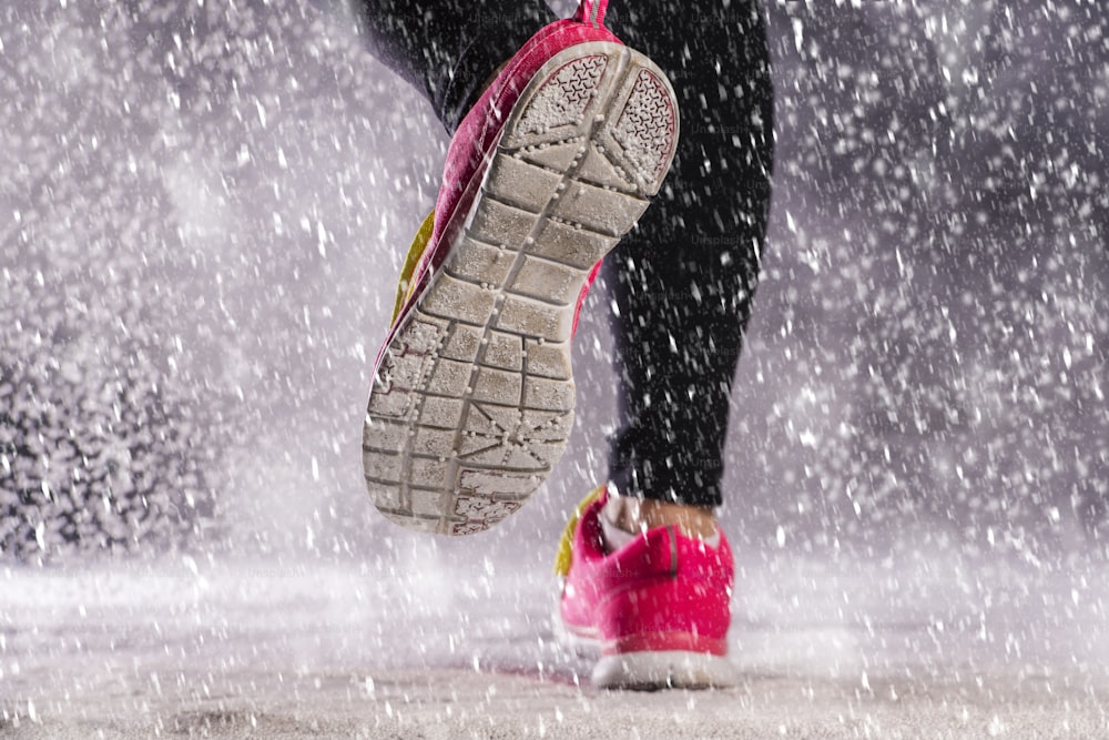 La mujer atleta está corriendo durante el entrenamiento de invierno al aire libre en un clima frío de nieve.