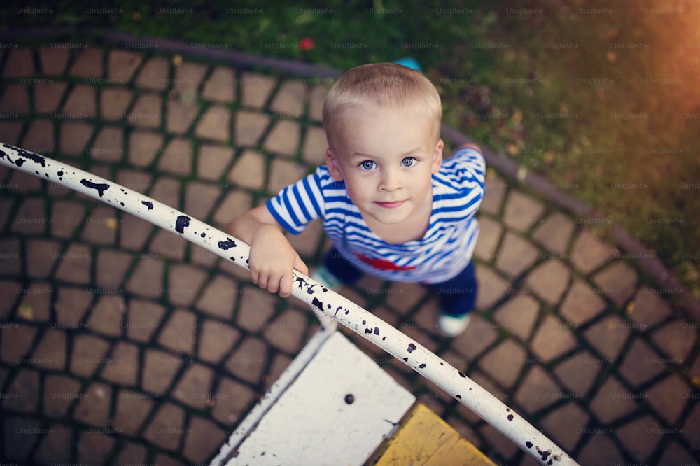 Mignon petit garçon dans un parc sur un vieux carrousel.