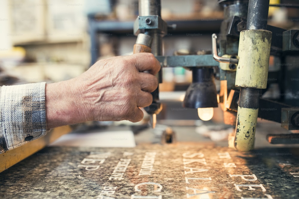 Senior man carving letters into marble plaque