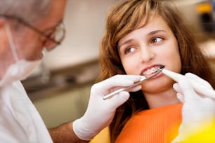 Adolescente com os aparelhos nos dentes está tendo um tratamento no dentista