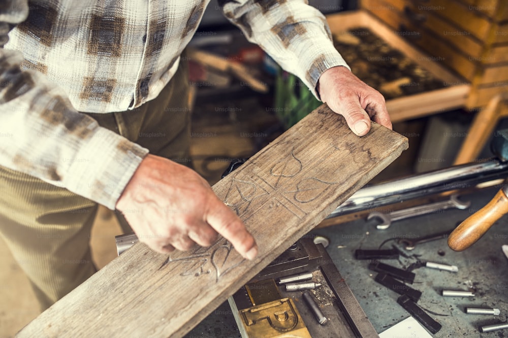 Homem sênior segurando em suas mãos tábua de madeira gravada