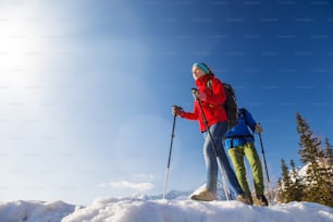 Young couple hiking outside in sunny winter mountains